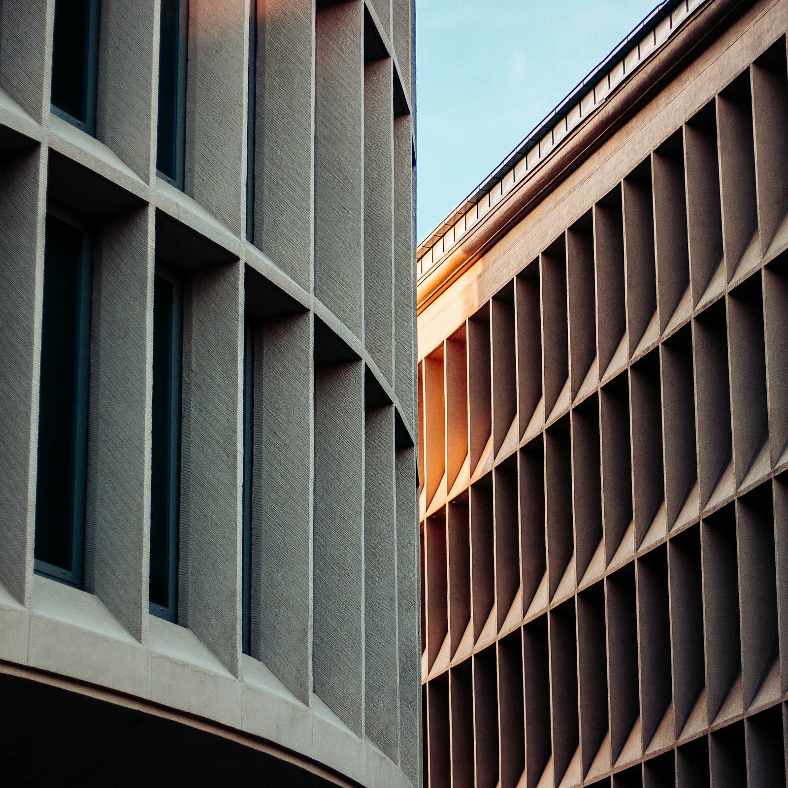 Curved concrete facade with deep window reveals, lit by low sun